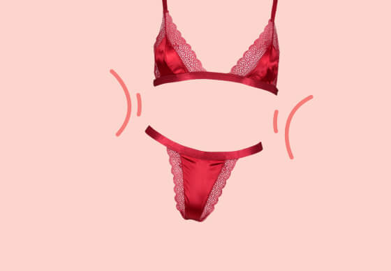 Red satin lingerie set—bra and thong—on a pink background